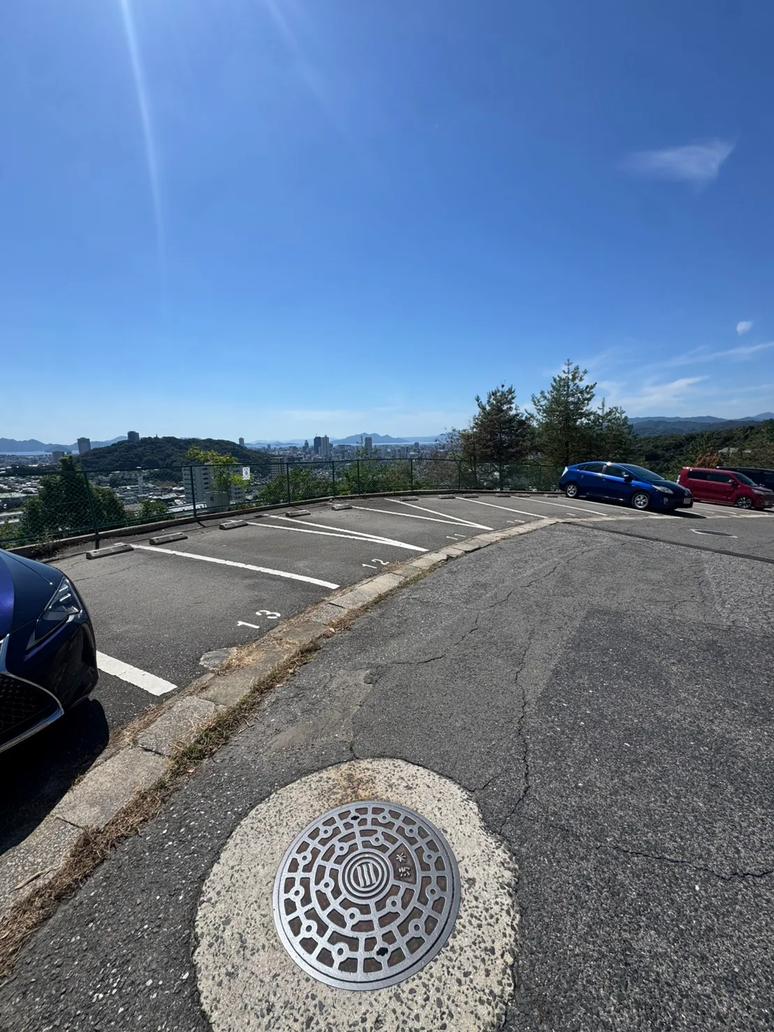 牛田早稲田で伐採を終えたマンション駐車場。カーブする通路に沿って駐車区画が並び、フェンスの外側には木々が残っている。