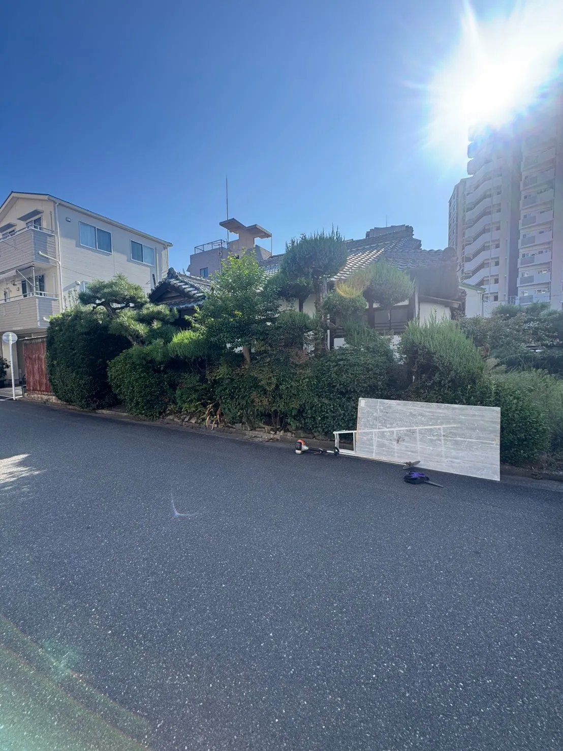三滝町の施工前。道路側に庭木や植栽が並び、住宅の一部が隠れている様子